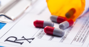 Opioid pills from a medicine box spilt all over a piece of paper on a clipboard 