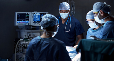 Medical professionals in masks and scrubs in operating room