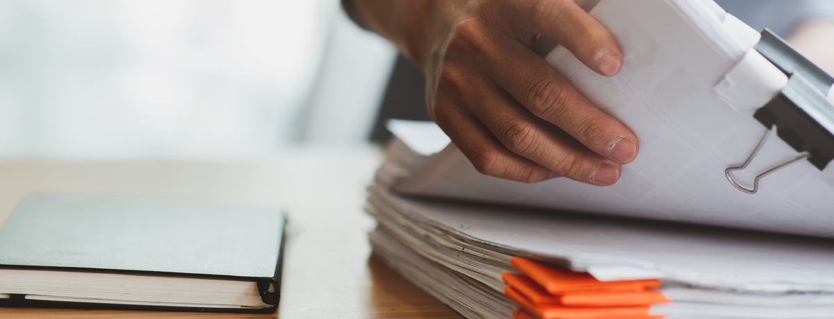 A racially ambiguous hand picks up papers that are clipped together