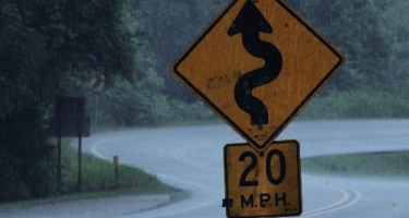 Traffic sign warning of curves ahead with 20 mph limit.
