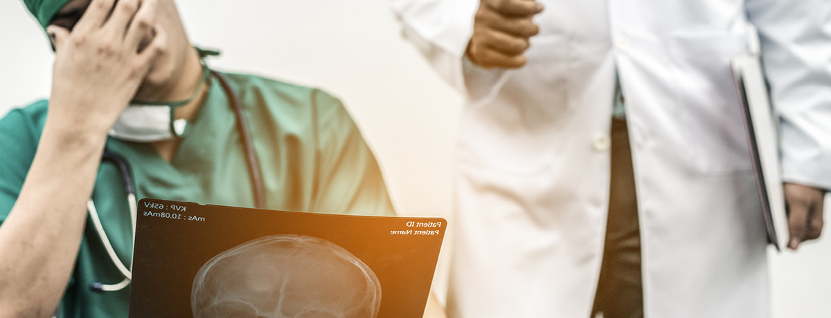 Doctor with hand on face reviewing scan with another doctor in backdrop