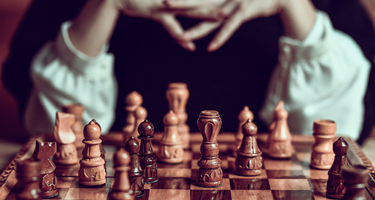 Female chess player with fingers crossed looks at chess set