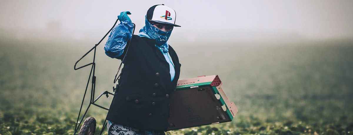 Worker wearing hat stands in field carrying equipment