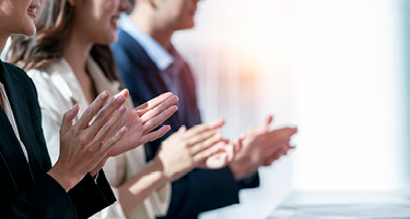 People in business suits standing in a line clapping