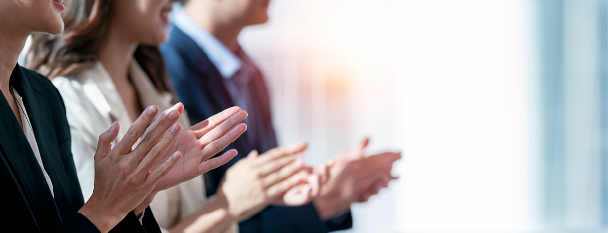 People in business suits standing in a line clapping