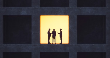 Black background made up of squares with one yellow square with black silhouettes 