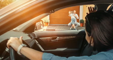Woman in car looking through window at man hugging child