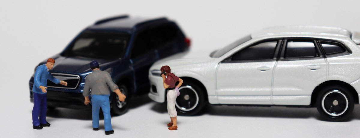 Toy cars crashed into each other with plastic toy people looking on