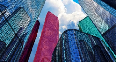 Blue skyscrapers with one pink one and one teal in the city
