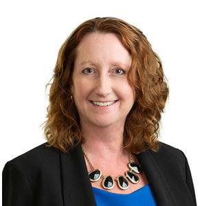 Woman with necklace and suit jacket poses for headshot