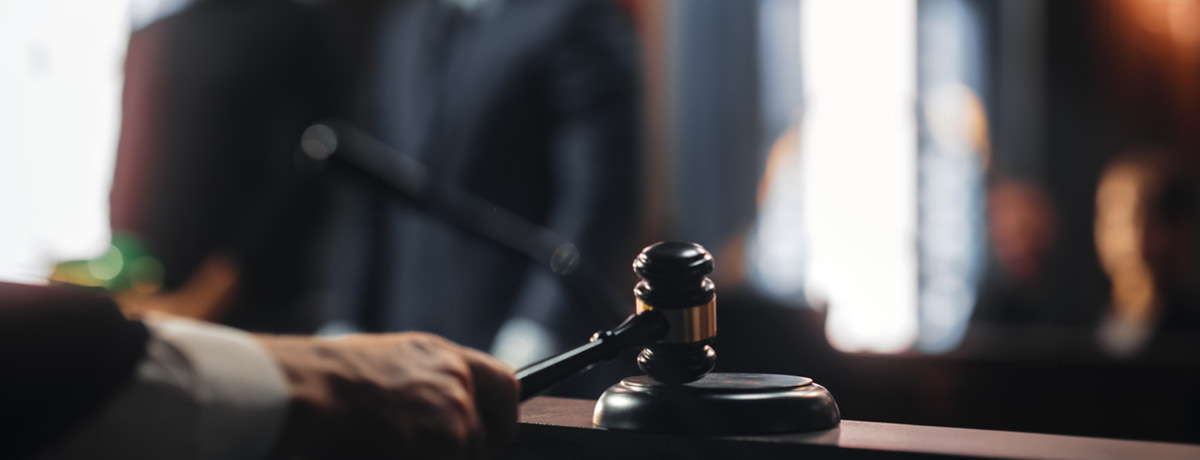 Hand holding gavel strikes down bench with people in backdrop