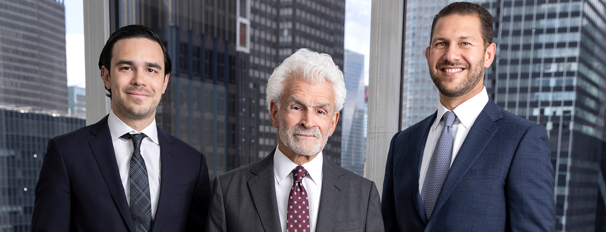 Three lawyers in suits pose for picture with cityscape in background