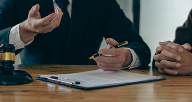 Lawyer out of view holds pen over contract