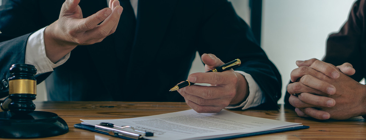Lawyer out of view holds pen over contract
