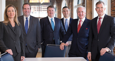Suited lawyers surround conference table for picture