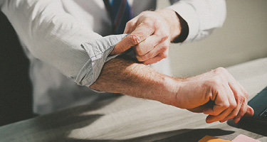 Unseen figure wearing suit rolls up sleeves