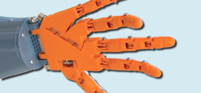 Close-up of an orange 3D-printed hand, illustrating advances.