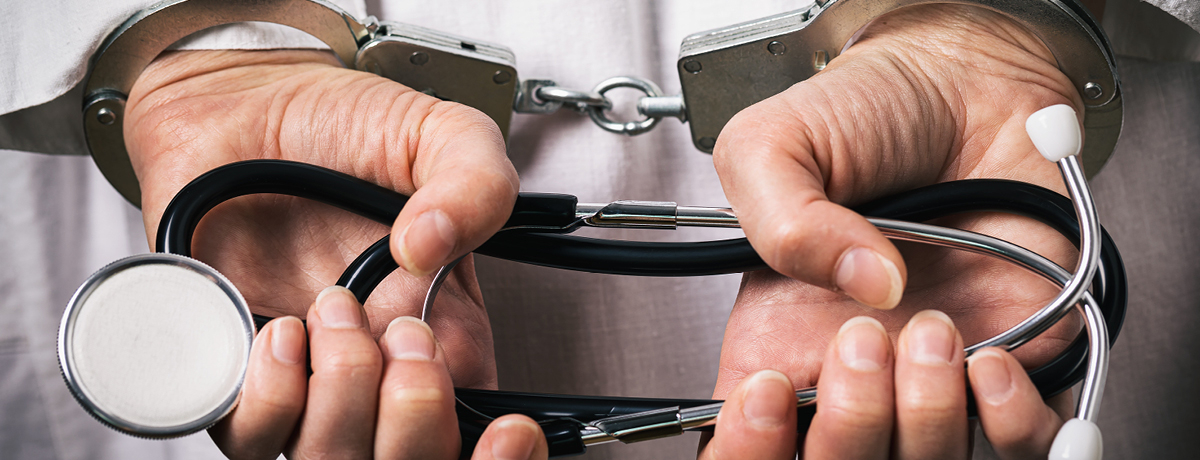 Doctor with hands behind back in handcuffs holding stethoscope