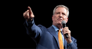 Black background with a man in a blue suit speaking out