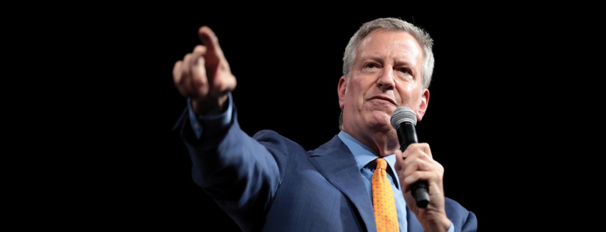 Black background with a man in a blue suit speaking out