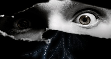 Black and white image of eyes looking through crack in wall