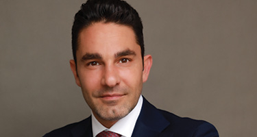 Man in suit with red tie poses for headshot