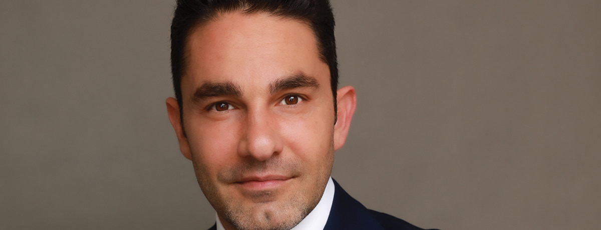 Man in suit with red tie poses for heashot