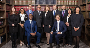 Salvi & Maher Law Firm group in front of legal library and cases of books