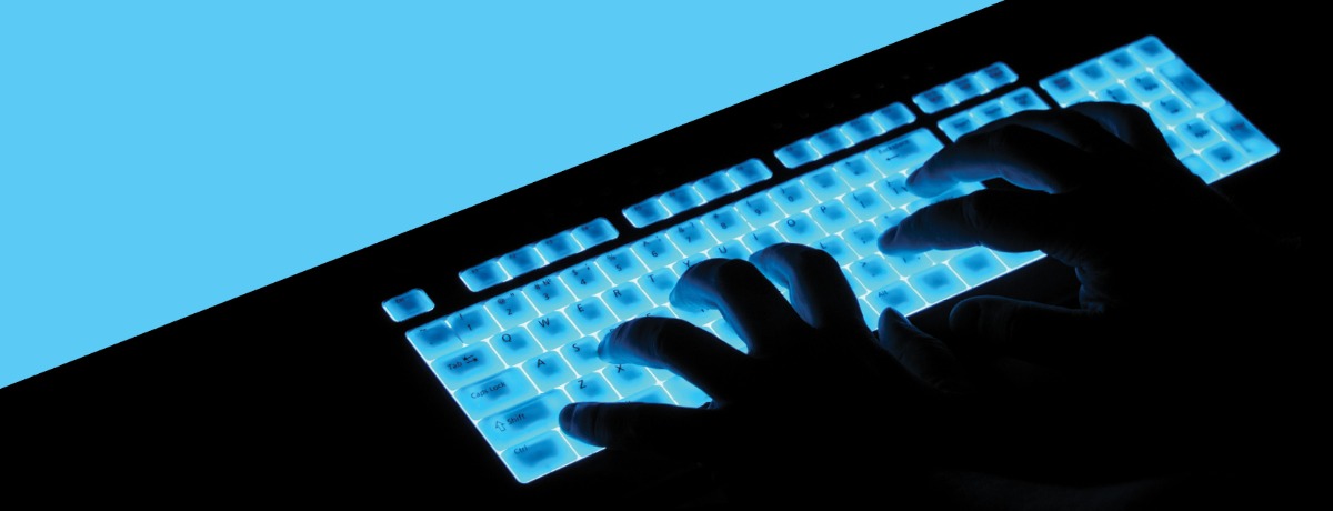 Hands typing on blue, light u keyboard