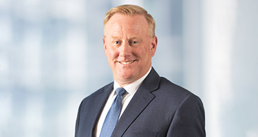 Medium portrait of a Caucasian male wearing a gray suit and blue tie