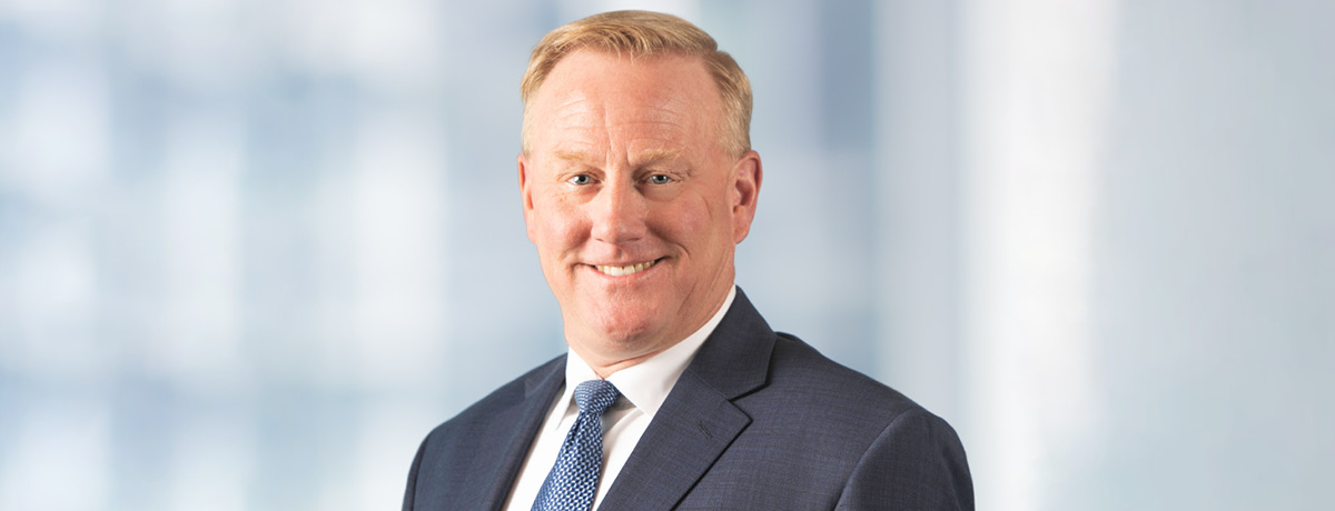 Medium portrait of a Caucasian male wearing a gray suit and blue tie