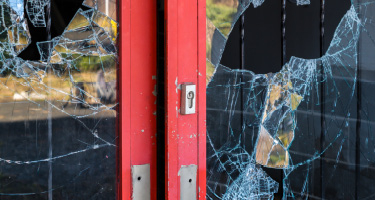 Red shop doors with glass broken open
