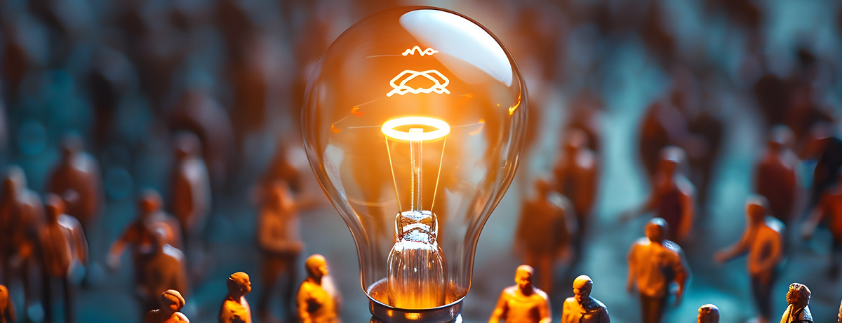 A glowing light bulb surrounded by a crowd of miniature figures