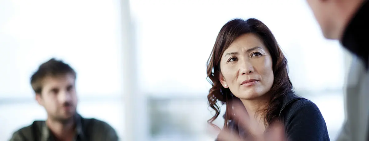 An In-Focus Woman Sitting Between Two Out-of-Focus Men at an Office Table