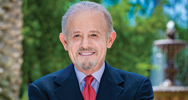 Man in blue suit with red tie standing outside