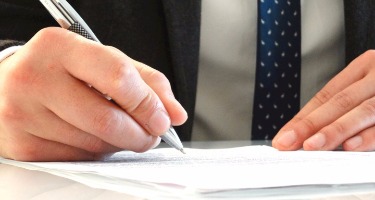 Male hands writing with a pen on a document