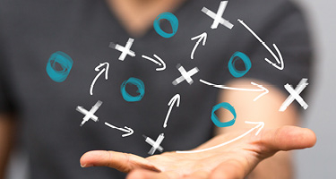 X's and O's and arrows on a board with person displaying them