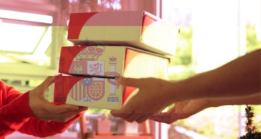 Two people exchange three boxes with Spanish symbol on the boxes 