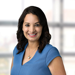 Woman with blue dress and necklace smiles for professional headshot