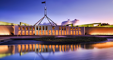 Australian Parliament beside water at sunset