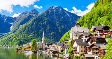 Austrian landscape of houses on water with mountain and blue sky in background