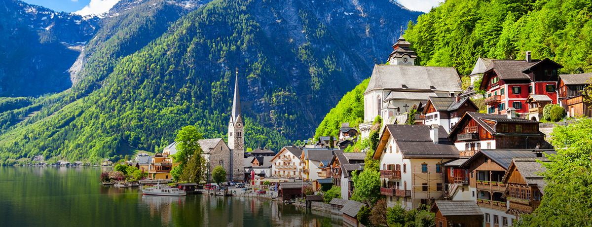 Austrian landscape of houses on water with mountain and blue sky in background
