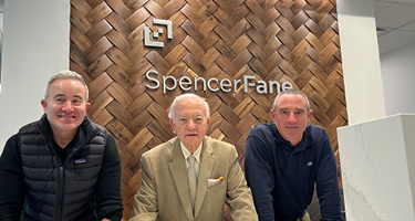 Three Spencer Fane Lawyers in Front of Firm Signage