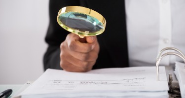 Person with magnifying glass reading Department of Justice additions