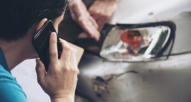 Man standing beside a damaged car after an accident