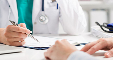 Doctor signing document while sitting across from a client