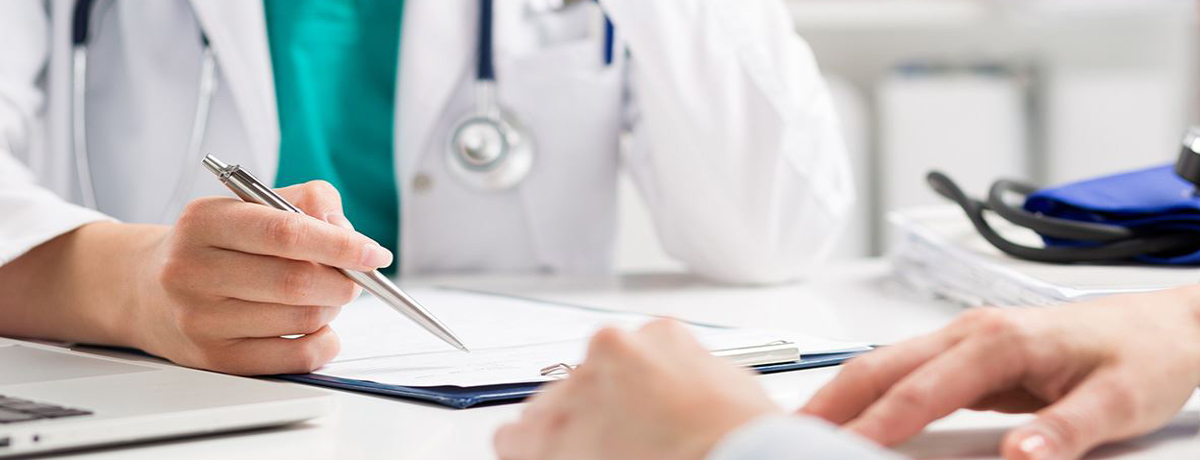 Doctor signing document while sitting across from a client