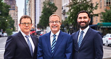 Three lawyers stand in NYC street posing for picture