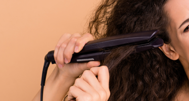 Brown background with a woman trying to straighten it curly hair