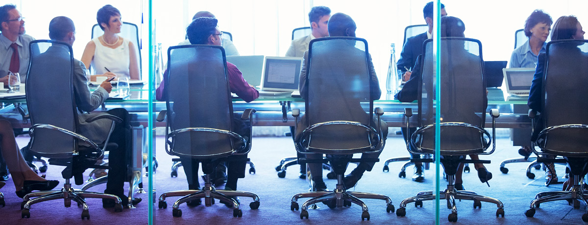 Several people sitting in chairs around boardroom table